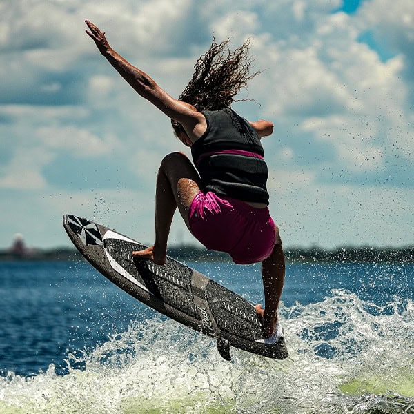 A woman surfing and jumping on her board in the ocean, showcasing an energetic water sport activity during a sunny day.