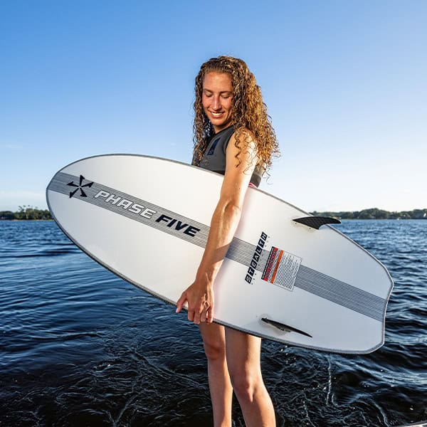 Girl holding a surfboard on a lake, enjoying sunny weather and water activities.